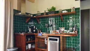 A kitchen with green tiles, wooden shelves, a dishwasher, and various kitchen utensils. - Vossehoeck 4 Apartment in Callantsoog (Callantsoog)