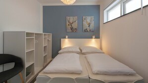 A bedroom with two beds, a wardrobe, and artwork on the wall. - Stuijvezandeweg 7Z for 2 Guests Near Centre (Callantsoog)