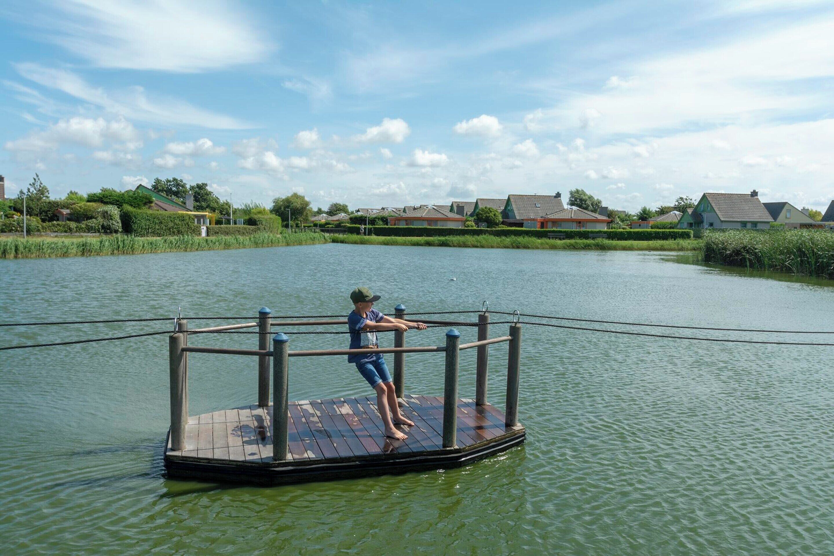 A wooden dock extending into a calm body of water with a person standing on it.