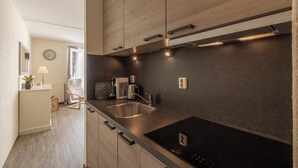 A modern kitchen with wooden cabinets, a black countertop, a built-in microwave, and a sink. - Apartment 189 in Julianadorp aan Zee (Julianadorp)
