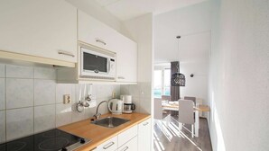 A modern kitchen with white cabinets, a wooden countertop, a built-in stove, a microwave, and a coffee maker. - Apartment by the Dunes Near the Sea (Julianadorp)
