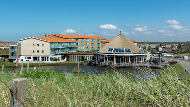 A hotel with a modern design, featuring a large building with a red roof and a circular structure with a conical roof. - Apartment by the Dunes Near the Sea (Julianadorp)