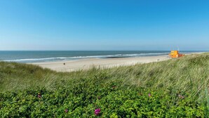 A beach with a lifeguard tower and grassy dunes.