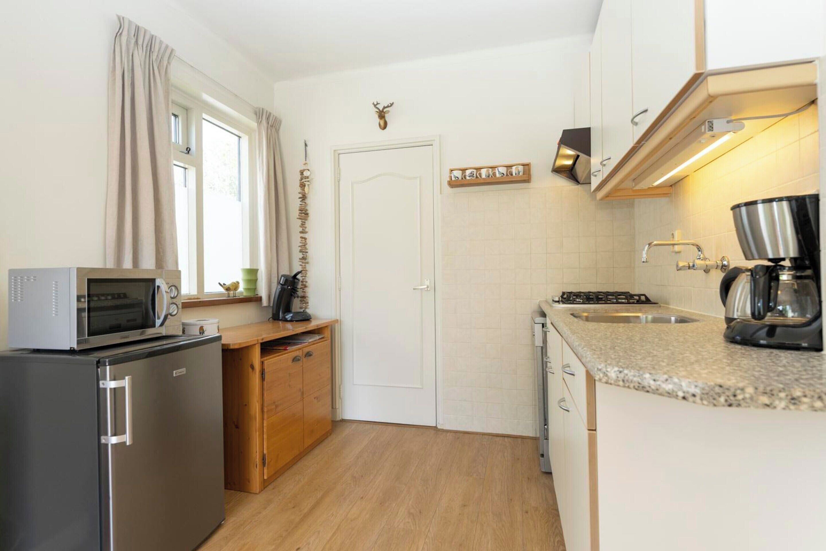 A compact kitchen with a refrigerator, microwave, stove, and sink.