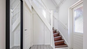 A staircase with white railings and a wooden floor, leading to a door. - Holiday Home in Texel Near the Beach (De Koog)