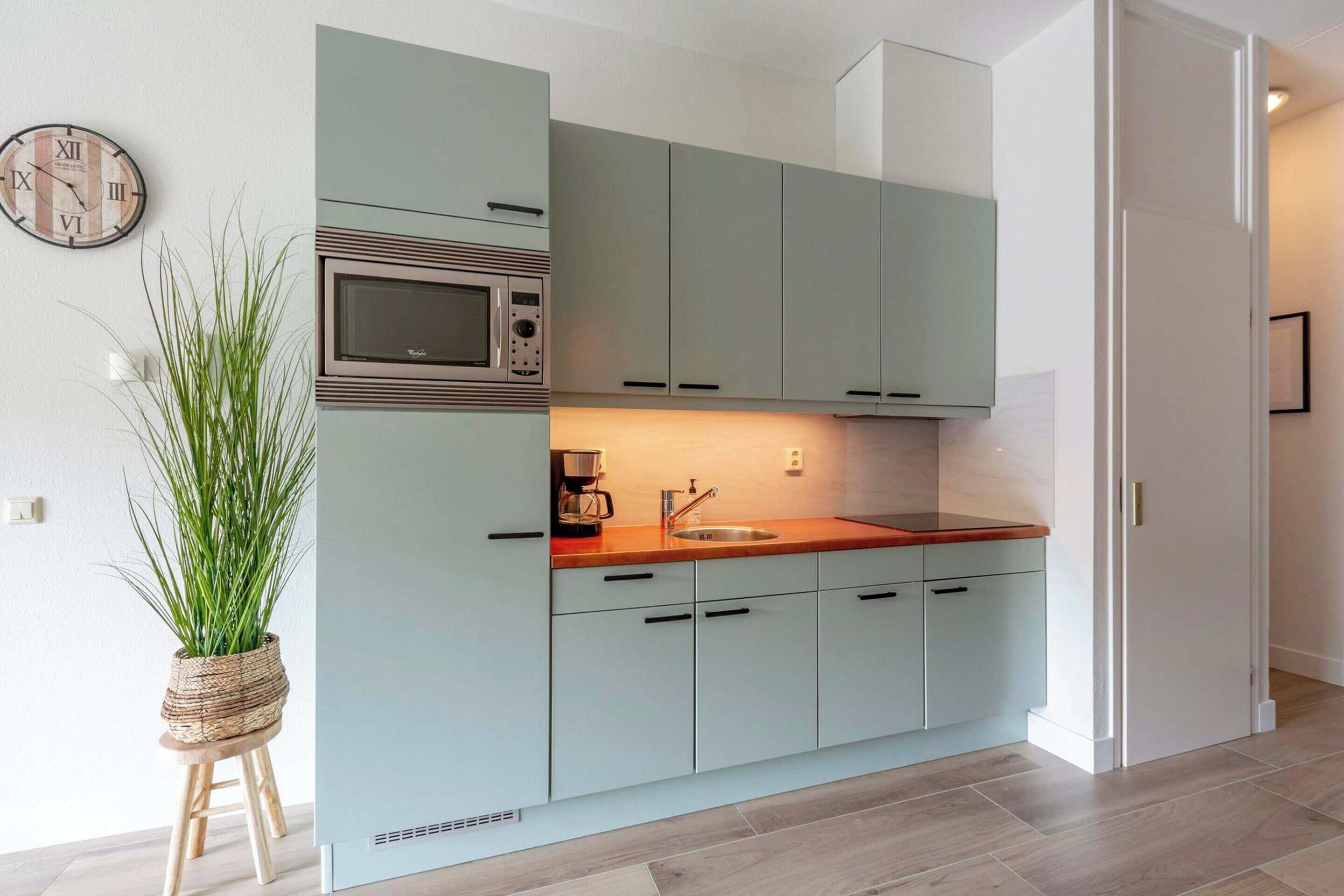 A modern kitchen with light blue cabinets, a microwave, and a coffee maker.