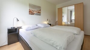 A modern bedroom with a large bed, bedside tables, a wardrobe, and a painting on the wall. - Modern Home Near the Beach (Julianadorp)