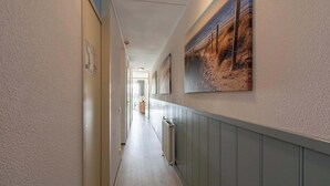 A hallway with a wooden floor, beige walls, and a radiator on the right. - Apartment by Dutch Beach Pet-friendly (Julianadorp)
