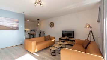 A modern living room with a sofa set, a TV, and a dining area.