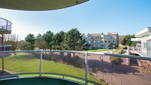 Vista da un balcone con piscina, su una zona verde curata e un edificio a più piani con un cartello che indica “RECEPTION”.