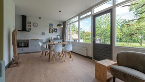 A modern kitchen with a dining area, large windows, and a view of greenery. - De Zeester 4-person Holiday Home n De Koog (Callantsoog)