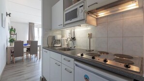 Une cuisine moderne avec des meubles blancs, un four à micro-ondes encastré, une cuisinière à gaz et une machine à café.