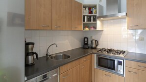 Una cucina moderna con mobili in legno, lavello in acciaio inox, fornello a gas, forno e macchina da caffè.