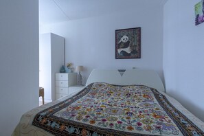 A bedroom with a bed, a nightstand, a dresser, a framed picture on the wall, and a window. - Stunning Apartment Near sea (Julianadorp)