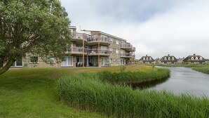 Un edificio residenziale con diversi balconi, una zona verde e un canale.