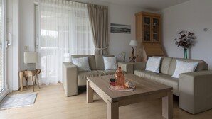 Un soggiorno con divano, tavolino in legno, mobile e lampada.
