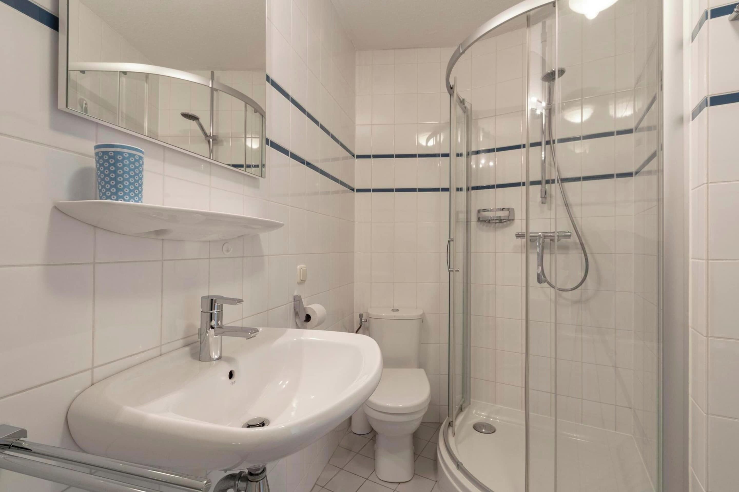 Ein Badezimmer mit einem weißen Waschbecken, einer Toilette und einer Duschkabine.