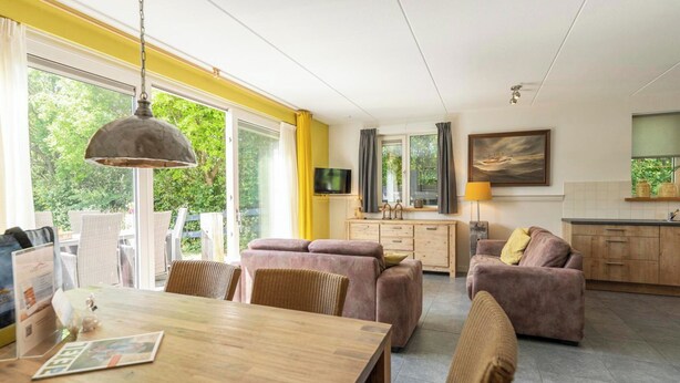 Een moderne woonkamer met een houten eettafel, twee banken en een televisie.