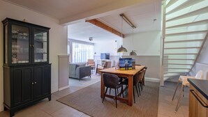 A spacious living area with a dining table, chairs, a cabinet, and a staircase. - Holiday Home in De Koog Near Beach (De Koog)