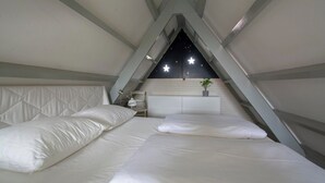 Quarto com duas camas, uma mesa de cabeceira e uma parede com um design estrelado.