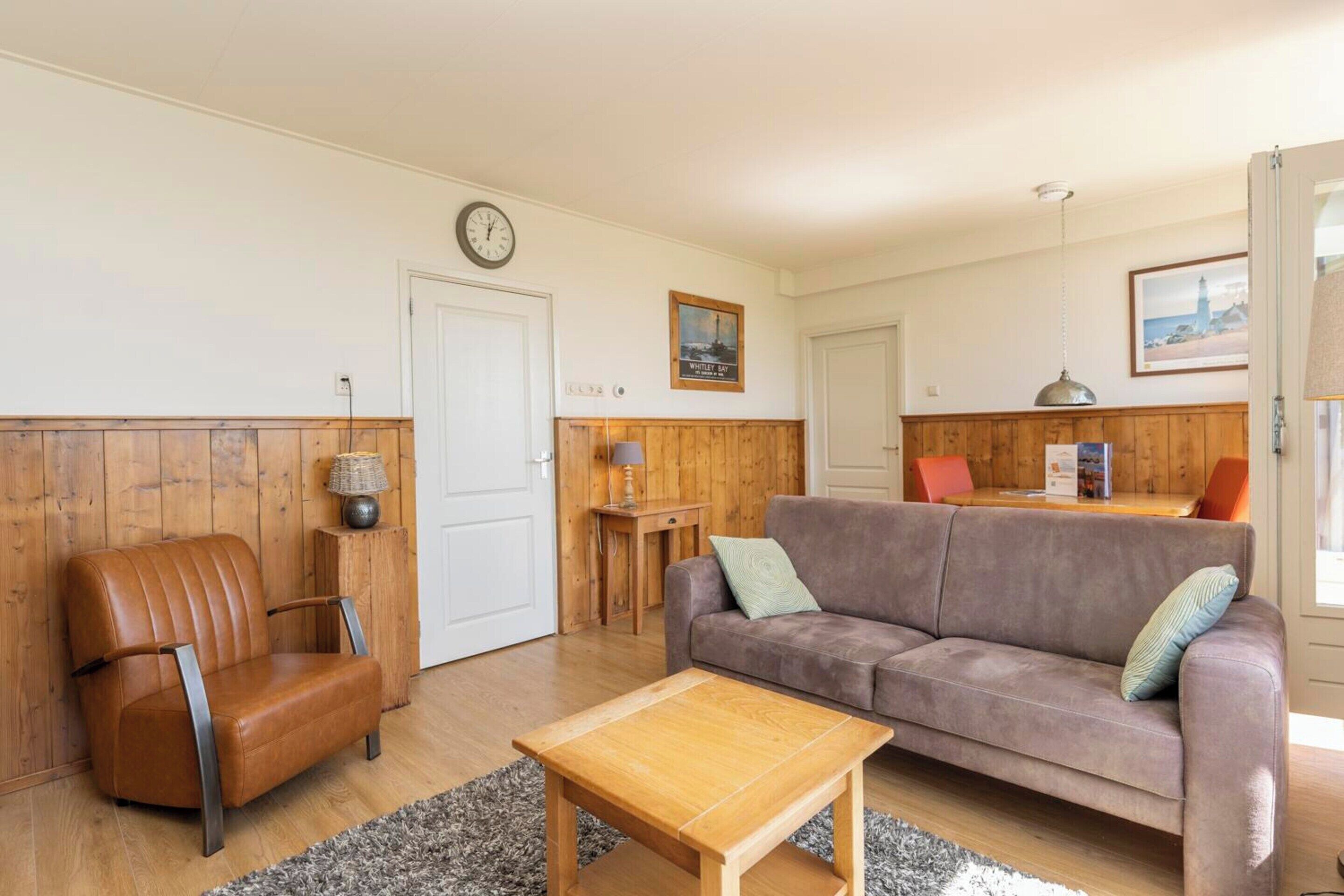 A living room with a brown leather chair, a brown sofa, a wooden coffee table, and a wooden cabinet.