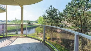 A balcony with a view of a river and trees. - Cozy Dune-view Apartment (Julianadorp)