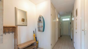 A hallway with a wooden bench, a mirror, and a shelf with a small item on it. - Cozy Dune-view Apartment (Julianadorp)