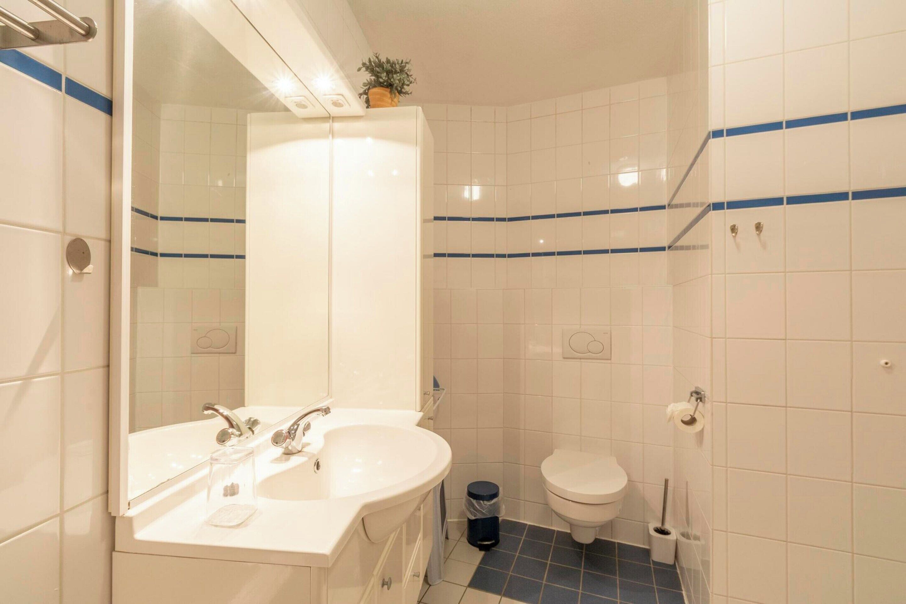 A bathroom with a white sink, mirror, and toilet.