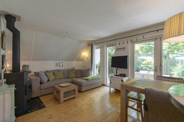 A cozy living room with a sofa, a TV, and a wooden table. - Elegant Holiday Home With Terrace (Burgerbrug)