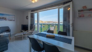 En moderne stue med spiseplads, store vinduer og udsigt over landskabet.
