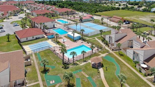 An aerial view of a resort with multiple swimming pools, a golf course, and beachfront properties.