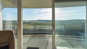 A room with a large sliding glass door leading to a balcony with a view of a landscape.