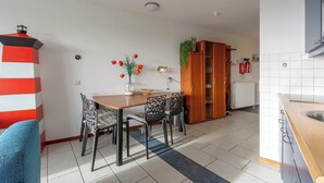 A modern kitchen with a wooden countertop, a dining area with a table and chairs, and a red and white striped wall.