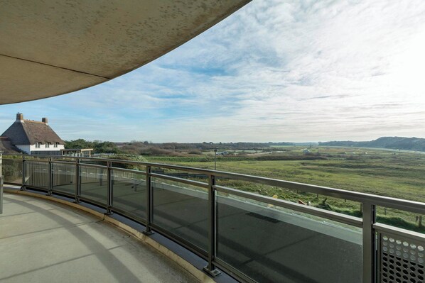 A balcony with a metal railing overlooking a road and a rural landscape. - Wijde Blick 205 Apartment With Balcony (Callantsoog)