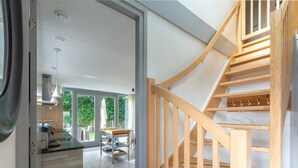 Ein modernes Interieur mit Küche, Essbereich und einer Holztreppe.
