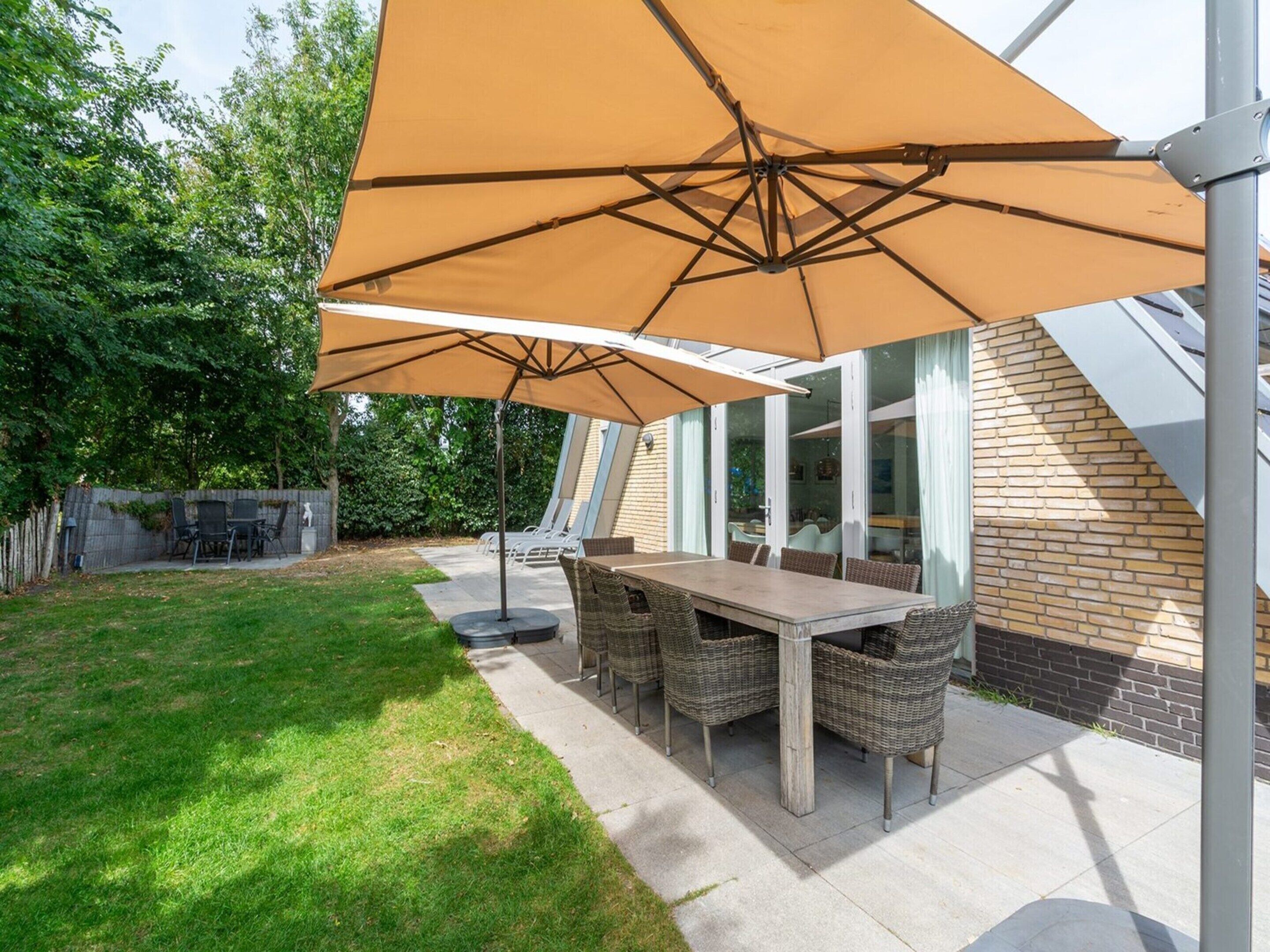 An outdoor patio with a table and chairs, a large umbrella, and a brick wall.
