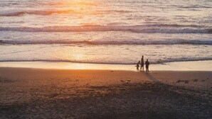 Eine Strandansicht mit Wellen und einem Sonnenuntergang.