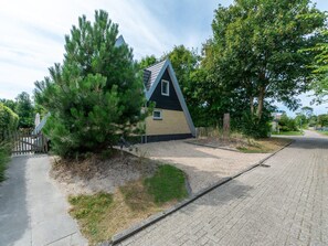 Ein modernes Haus mit geneigtem Dach, einem kleinen Fenster und einem gepflasterten Auffahrt.