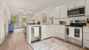 A modern kitchen with white cabinets, stainless steel appliances, and a central island.