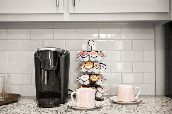 Une machine à café, une tasse et un support à dosettes de café sur un plan de travail de cuisine.