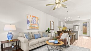 A modern living room with a sofa, coffee table, and a dining area with a chair and table.