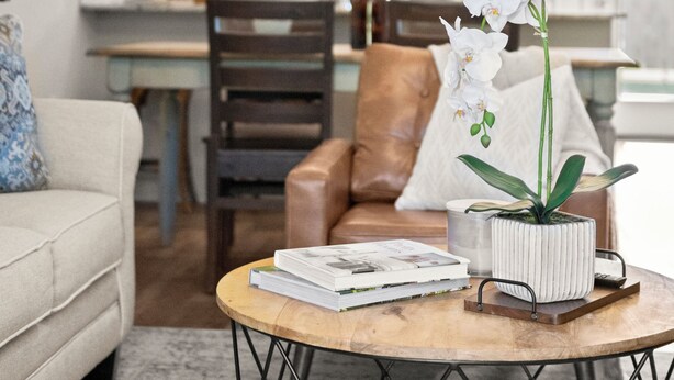 A modern living room with a round coffee table, a sofa, and a dining area in the background.