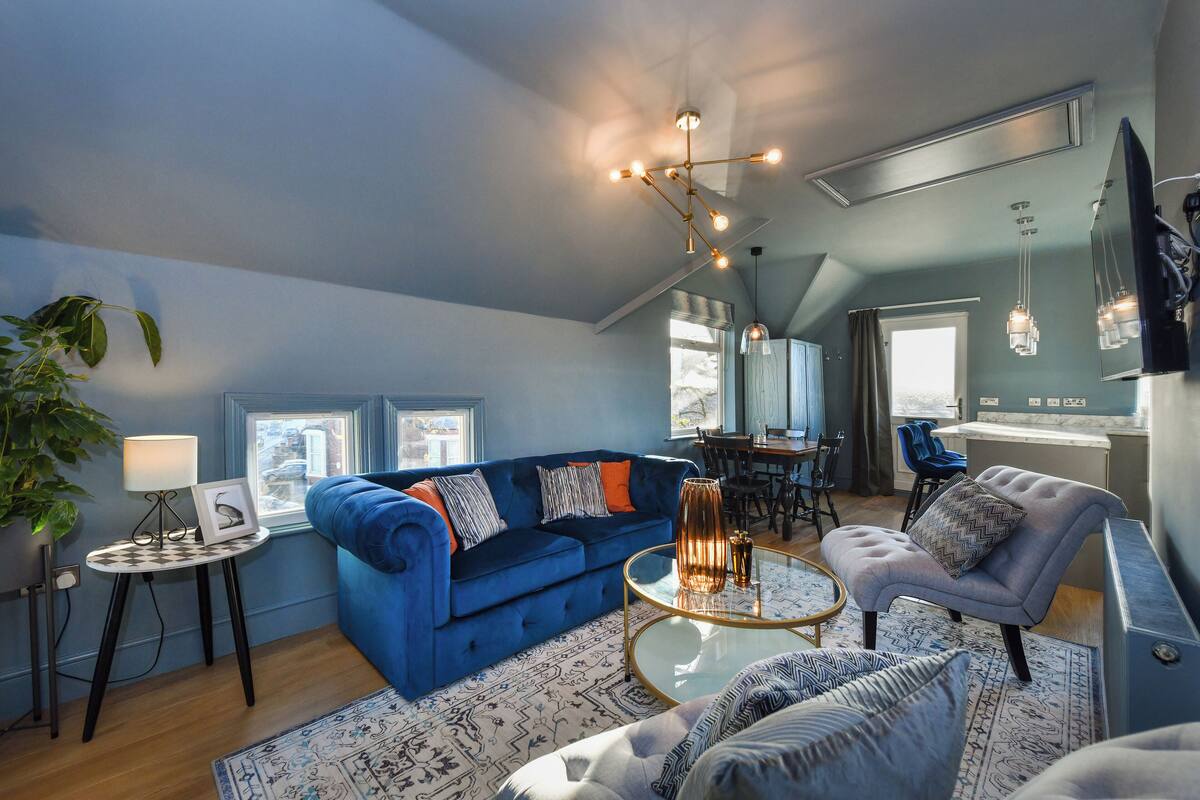 A modern living room with a blue sofa, a round coffee table, and a blue armchair.