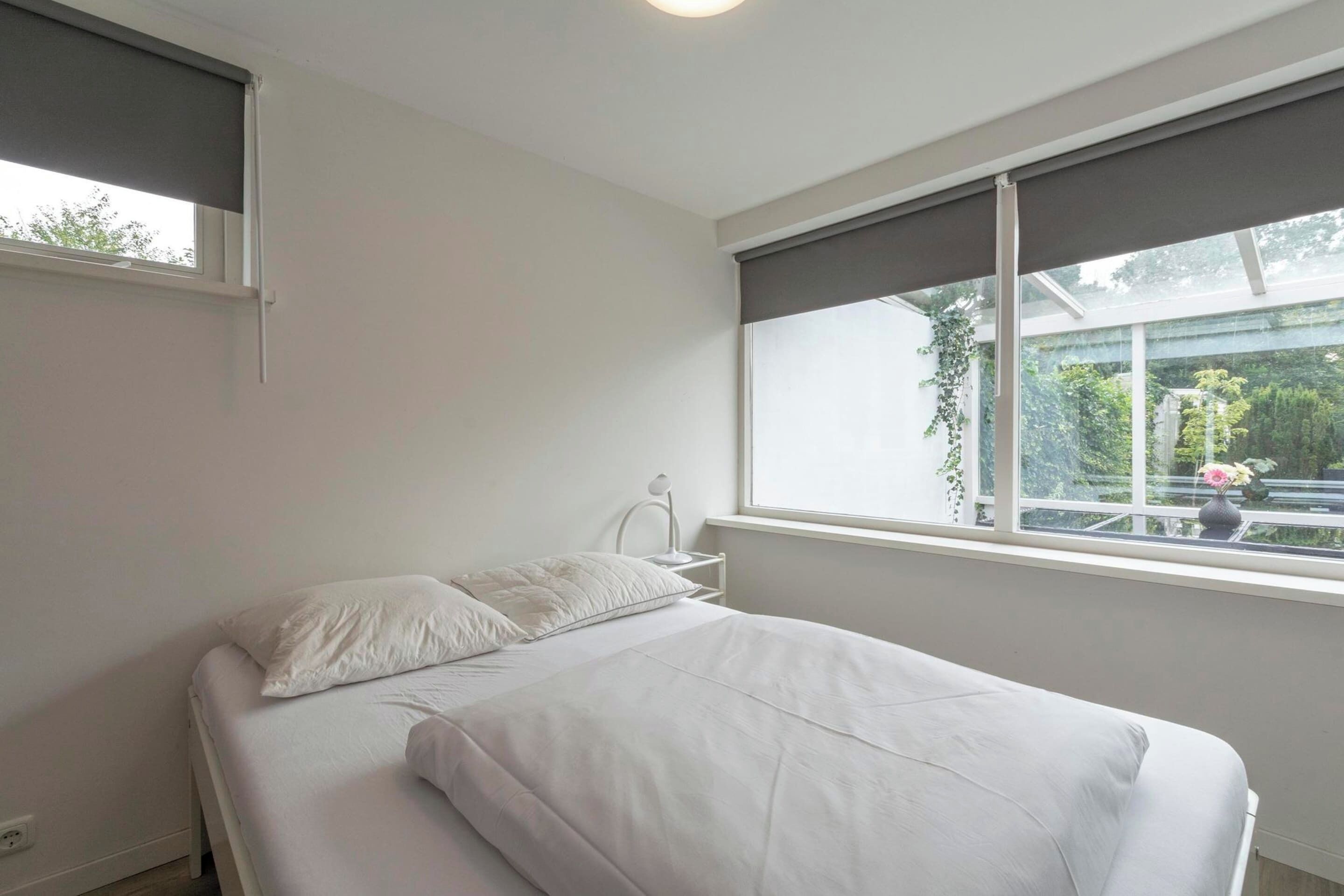 Een slaapkamer met een bed, een raam en een nachtkastje.