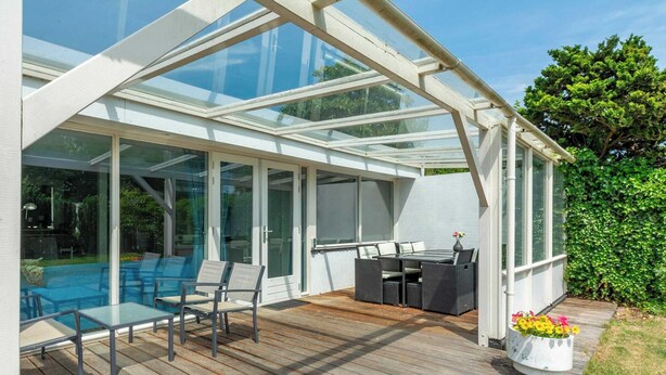 A sunroom with a glass ceiling, a pool, and outdoor furniture. - Bungalow in Sint Maartenszee Near Beach (Sint Maartensvlotbrug)
