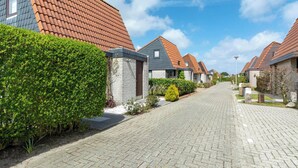 A residential street with houses featuring red-tiled roofs and grey stone facades. - Yperhof 66 Holiday Home for 6 Guests on Cost (Julianadorp)