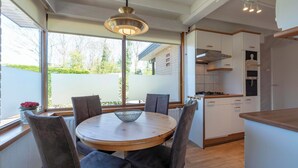 A modern kitchen with white cabinets, a wooden countertop, and a hanging light fixture. - Wildrijk 152 Holiday Home in Sint Maartenszee (Sint Maartensvlotbrug)