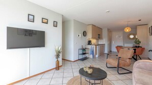 Un salon moderne avec un téléviseur à écran plat, une table basse ronde et un canapé confortable.