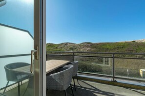 A balcony with a table and chairs, offering a view of the landscape. - Pet-friendly Apartment (Callantsoog)