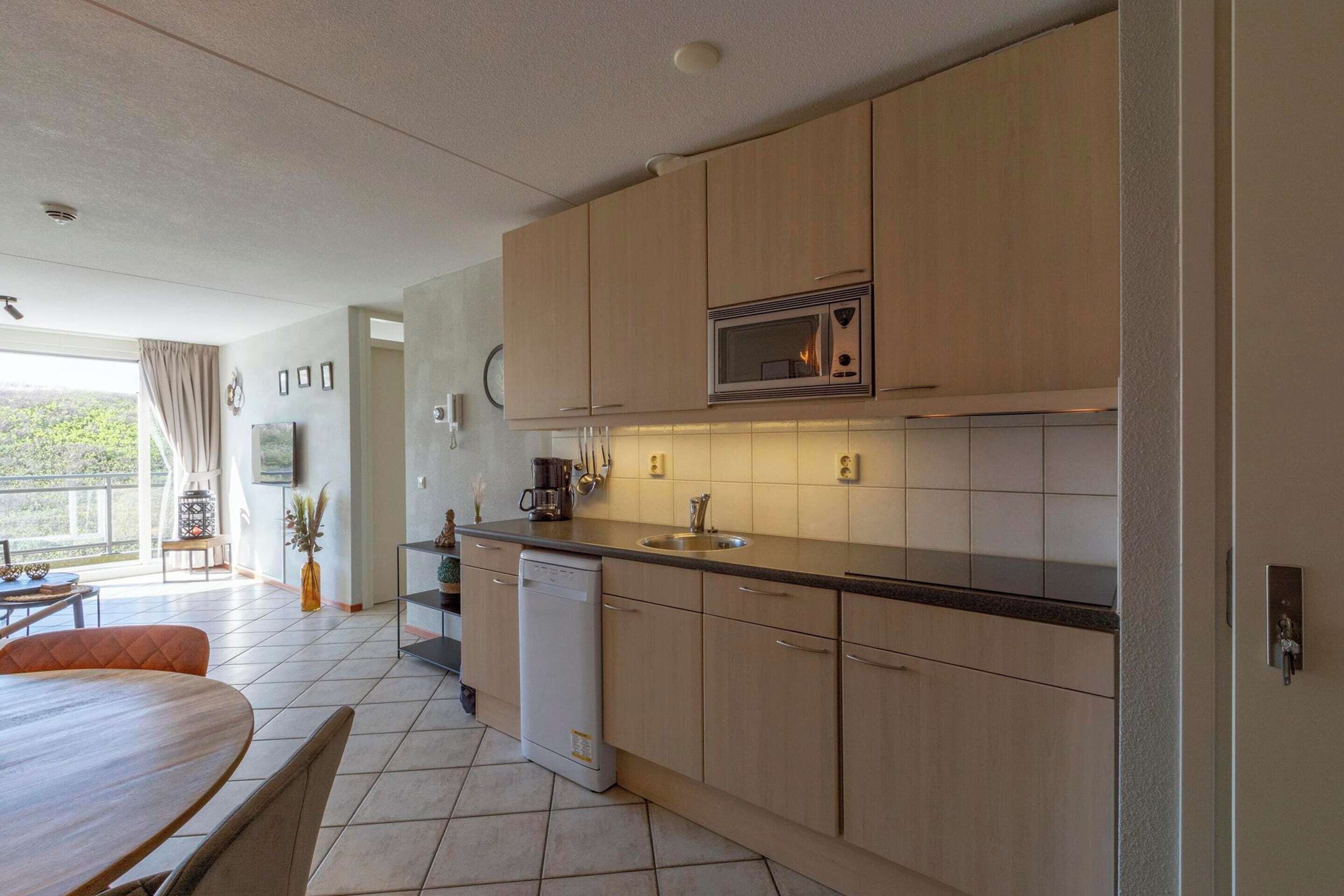 A modern kitchen with wooden cabinets, a microwave, a dishwasher, and a sink.